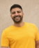man in yellow crew neck t-shirt and black denim jeans standing beside white wall